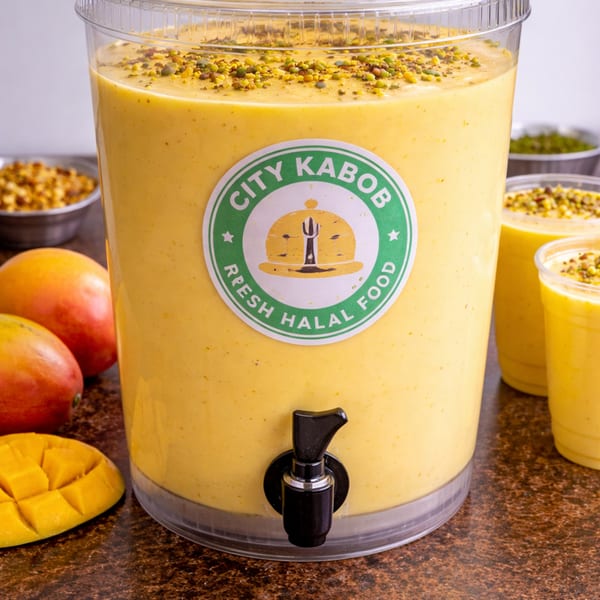 Large City Kabob mango lassi dispenser with whole and sliced mangoes, and two smaller cups.